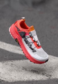 Trail running shoe with a white, grey, and bright orange upper; features a Boa fastening system and textured pink outsole for grip.
