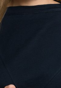 Donker marineblauwe katoenen shirt met een ronde halslijn en zichtbare stikseldetails. Heeft een zachte textuur en een eenvoudig, klassiek ontwerp.