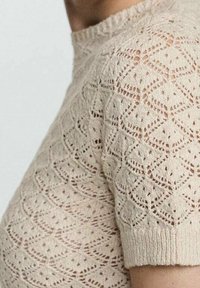 Gebreid shirt met korte mouwen in beige, voorzien van een gestructureerd ruitpatroon en een ronde hals. Lichtgewicht en ademend materiaal.