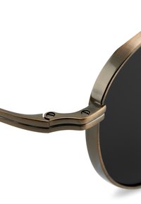 Metalliset aurinkolasit tummilla linsseillä, joissa on vintage pronssiviimeistely, kaareva muotoilu ja korostettu saranat, joissa on näkyvät ruuvit.