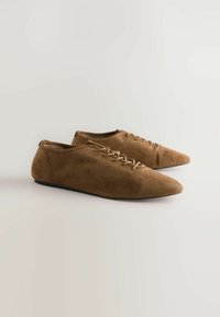 Scarpe lacci in suede marrone con punta affusolata, caratterizzate da una texture liscia, design minimalista e una suola nera bassa.