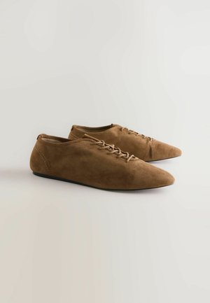 Smeđe suede cipele s vezanjem i oštrim vrhom, s glatkom teksturom, minimalističkim dizajnom i niskim crnim potplatom.