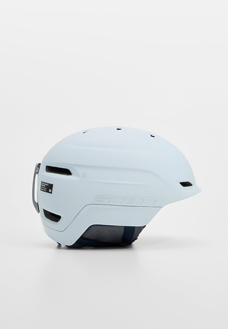 Kask Scott w matowym jasnoniebieskim kolorze, o opływowym kształcie, z otworami wentylacyjnymi, regulowanym paskiem i widocznym detalem logo z boku.