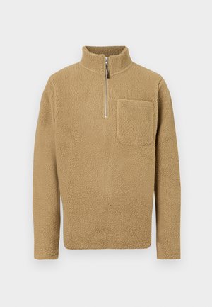 Beige fleece pullover met een hoge kraag en halve rits. Beschikt over een voorkant zak en een gestructureerd oppervlak voor extra warmte en comfort.