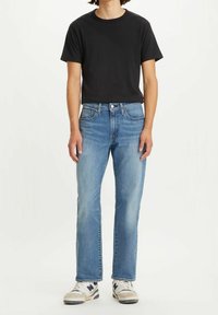 Camiseta negra de manga corta combinada con jeans rectos de color azul claro. Los jeans tienen una textura deslavada y un diseño tradicional de cinco bolsillos.