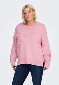 Suéter de punto rosa con un corte holgado, puños y dobladillo acanalados, con diseños florales en un rosa más oscuro en la parte delantera y la manga.