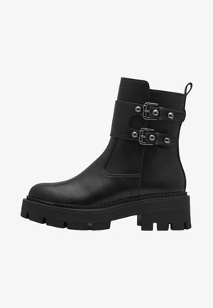 Schwarze Leder-Ankle-Boots mit einer dicken Sohle, ausgestattet mit zwei verstellbaren Riemenschnallen und einer Schlaufe zum Hochziehen an der Rückseite.