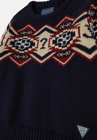 Maglione blu navy con motivi geometrici rossi, crema e neri sulla parte anteriore e sulle spalle, caratterizzato da motivi di punto interrogativo e etichette del logo Guess.