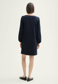 Abito a maniche lunghe blu navy con vestibilità dritta e scollo rotondo. Tessuto morbido, maniche a sbuffo arricciate e orlo fino al ginocchio.