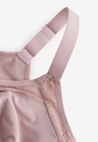 Soft pink bra strap and cup featuring adjustable metal slider and lace trim on smooth fabric background.