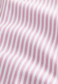 Rozā un baltas svītras audums ar smalku tekstūru, kurā maiņojas gludas un teksturētas svītras, veidojot austā rakstu.