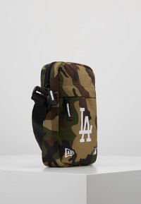 Borsa a spalla con motivo camouflage realizzata in tessuto resistente, con logo bianco "LA", zip nera e tracolla regolabile.