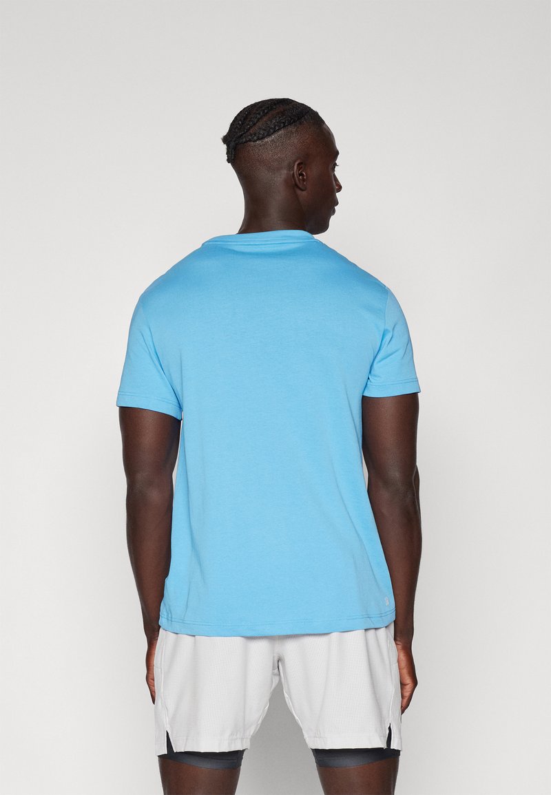 Lichtblauw T-shirt met korte mouwen van zachte stof, met een ronde halslijn en een relaxte pasvorm, van achteren bekeken.