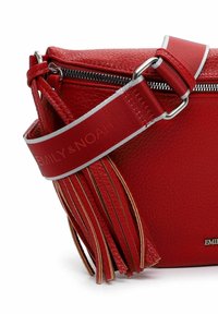 Borsa crossbody in pelle rossa con chiusura a zip, dotata di una tracolla con dettagli argentati e frange decorative. Logo del brand esposto.