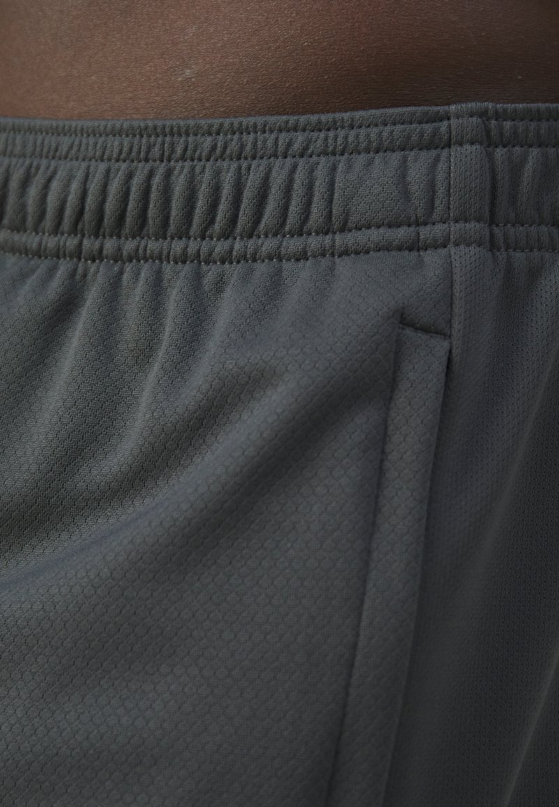Shorts deportivos de color gris oscuro con tejido texturizado, cinturilla elástica y bolsillos laterales. El material presenta un sutil patrón hexagonal.