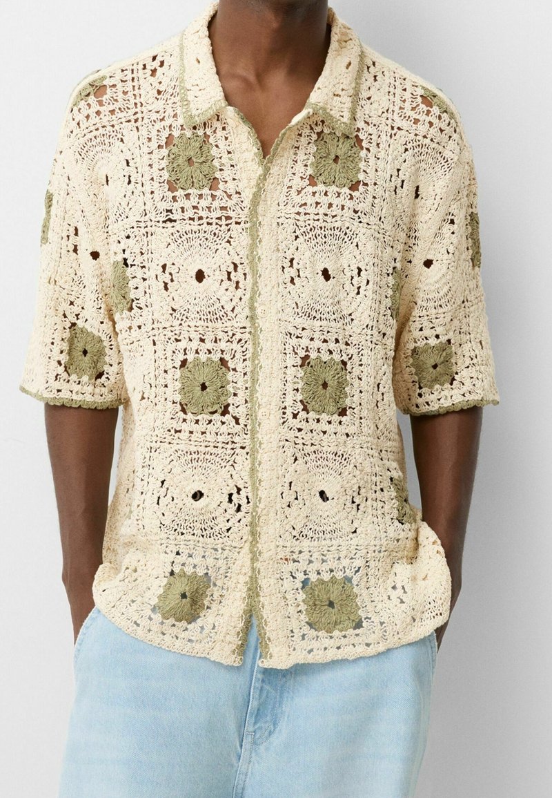 Gehaakt shirt met een patroon van lichtbeige en olijfgroene vierkanten. Korte mouwen, knoopsluiting aan de voorkant en een gestructureerde stof.