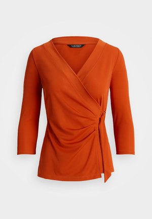 Blouse portefeuille à manches longues orange rouille avec détail froncé sur le côté, fermeture par lien latéral, col en V et manches trois-quarts.