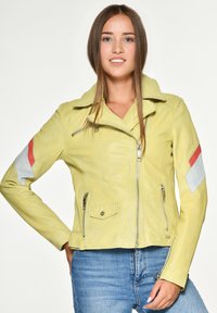 Geel leren jack met een ritssluiting aan de voorkant, oversized kraag en een getailleerd ontwerp; bevat grijze en rode patches op de mouwen.