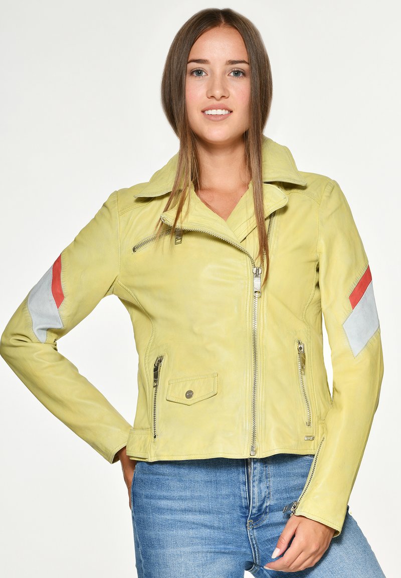 Geel leren jack met een ritssluiting aan de voorkant, oversized kraag en een getailleerd ontwerp; bevat grijze en rode patches op de mouwen.