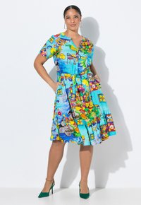 Kurzes Kleid mit kurzen Ärmeln aus einem lebhaften blauen Stoff mit bunten Mustern, darunter Früchte, Tiere und Gebäude; enthält einen Gürtel und Taschen.