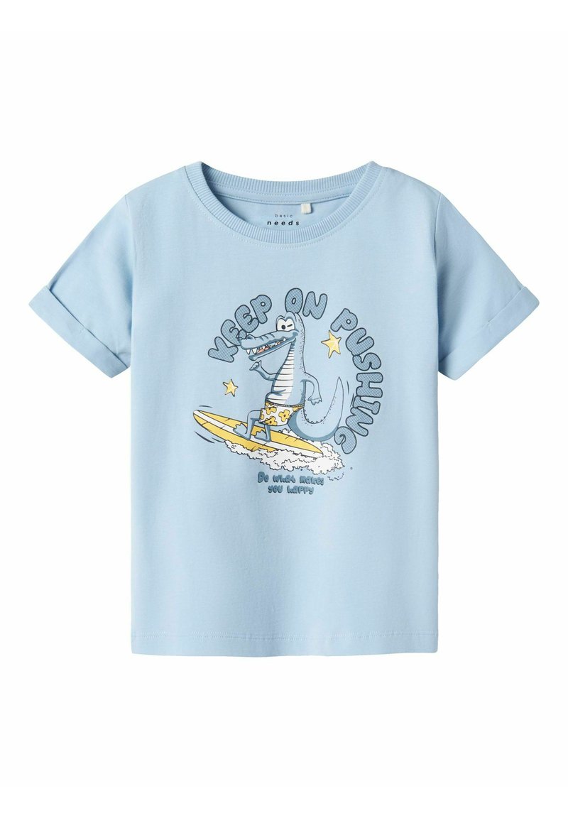Camiseta de manga corta azul claro, hecha de algodón, que presenta un cocodrilo de dibujos animados surfeando con el texto "SIGUE ADELANTE" en negro y amarillo.