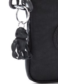 Borsa in tela nera con una superficie texturizzata, dotata di un portachiavi in cromo lucido su cui è attaccato un charm a forma di scimmia in gomma nera.