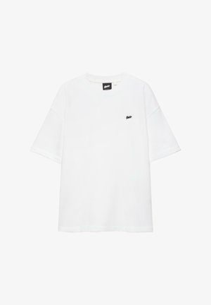 Fehér, rövid ujjú, kerek nyakú póló, bal mellrészen kis fekete logóval és a nyakkivágás belsejében fekete márkajelzéssel.