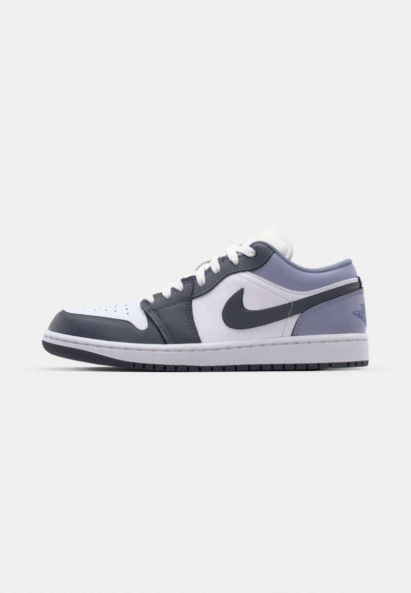 Scarpe Nike con tomaia in pelle bianca e dettagli grigi, punta arrotondata e suola imbottita. Il design include un logo ben visibile.