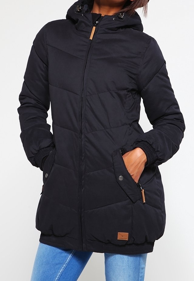 Veste rembourrée noire avec capuche, dotée d'une fermeture éclair, de poignets côtelés et de deux poches latérales. Accentuée d'une patte de logo beige à l'ourlet.