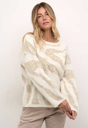 Pull crème avec un motif abstrait beige texturé, des manches larges et un col rond. Tissu en maille doux.