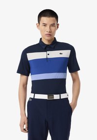 Polo shirt bleu marine avec des rayures horizontales en bleu clair et blanc ; doté d'une patte de boutonnage et d'un logo brodé sur la poitrine.