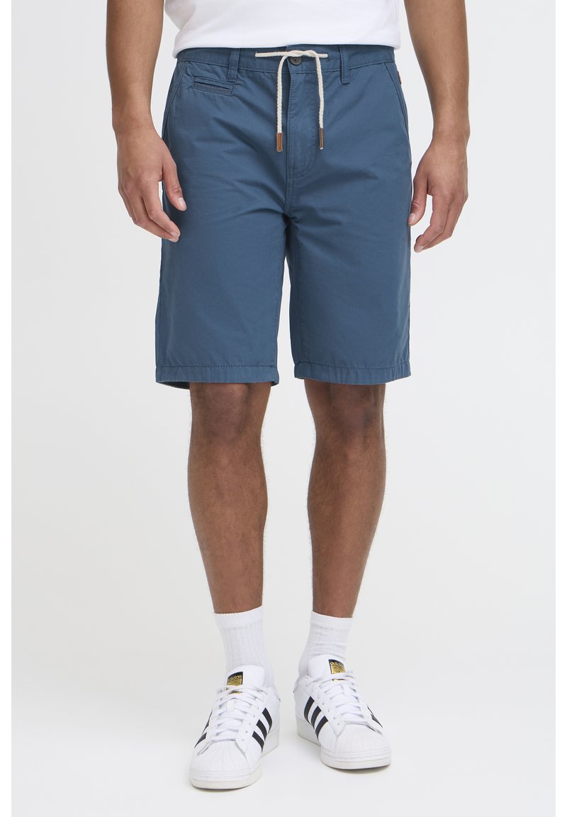 Pantalones cortos casuales azules hechos de tejido ligero. Cuentan con una cintura de cordón con detalles de cuero. A la altura de la rodilla y con una textura suave.