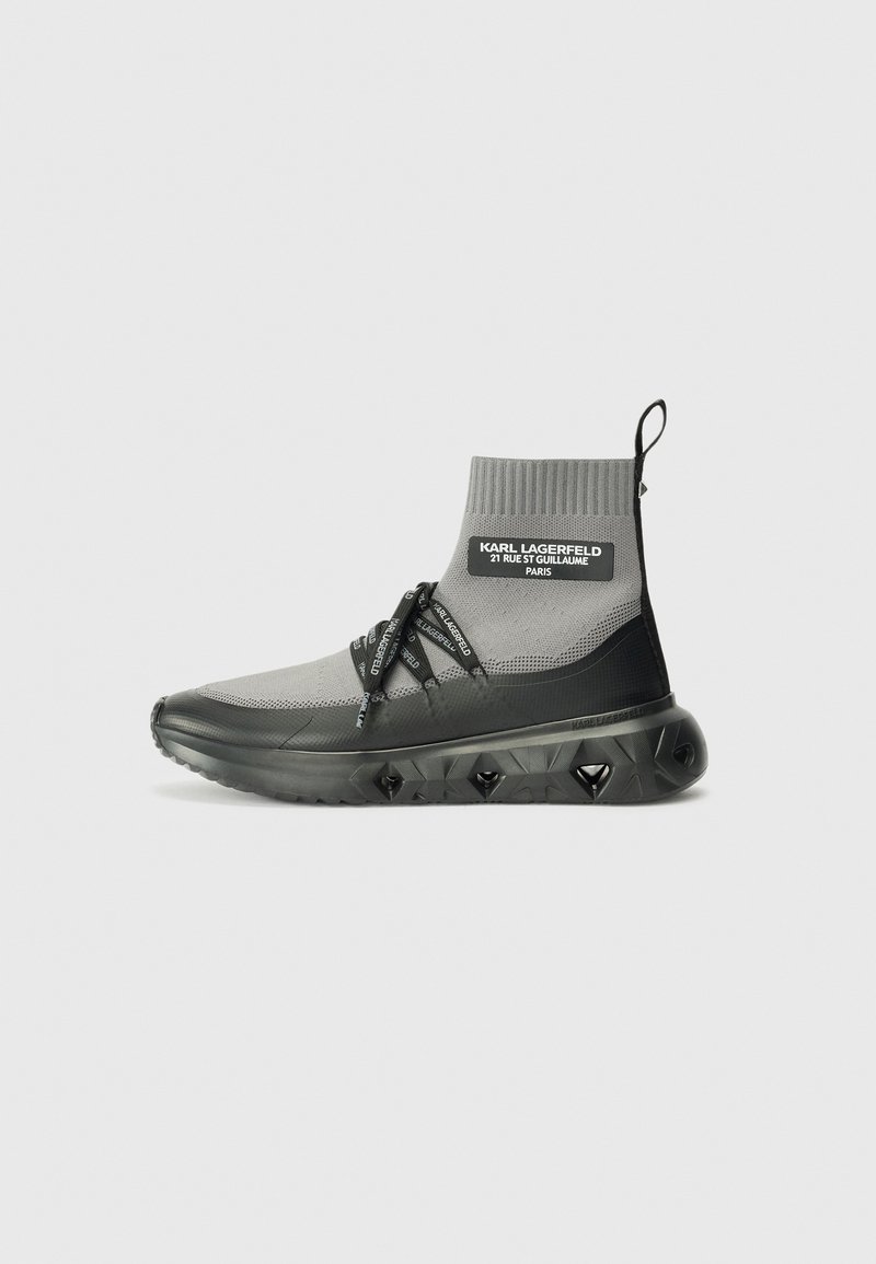 Gray and black ankle-high sneaker with knit upper, drawstring closure, and textured sole featuring diamond patterns and logo accents.