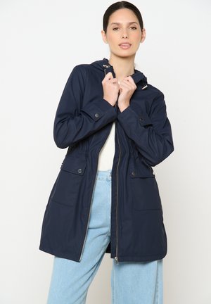 Veste à capuche bleu marine en matériau imperméable, dotée d'une fermeture éclair à l'avant, d'une taille à cordon de serrage et de deux poches avant avec fermeture à pression.