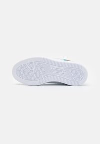 Podeszwa sneakersów Puma w białej gumie z teksturowanym wzorem antypoślizgowym, z wytłoczonym logo PUMA oraz aktywnym designem wkładki, przeznaczona do użytkowania, które nie pozostawia śladów.