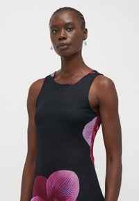 Robe noire sans manches avec une grande impression florale d'orchidées violettes sur le côté, dotée d'un col rond et d'une texture lisse et ajustée.