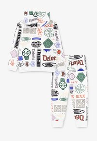 Ensemble sweat-shirt et pantalon blanc avec divers logos imprimés et graphiques en bleu, vert, rouge et noir. Tissu doux et lisse avec des poignets côtelés.