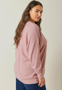 Hellrosa gestreifter Pullover mit langen Ärmeln, lockerer Passform und rundem Halsausschnitt. Die Textur zeigt zarte vertikale Streifen und umgeschlagene Ärmel.