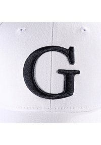 Casquette de baseball blanche avec une grande lettre "G" brodée en noir à l'avant. Fabriquée en tissu texturé avec une visière incurvée.