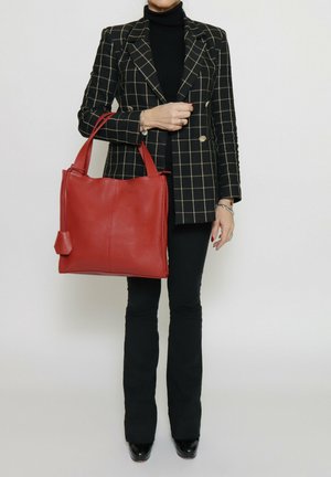 Red leather tote bag with a textured finish and two sturdy handles. Features a side pocket with a decorative accent.