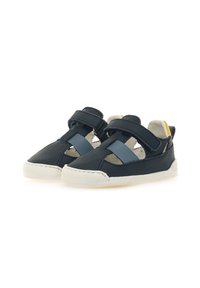Zapatos infantiles de cuero en color navy con correas azules, lados abiertos y suela de goma blanca. Presenta detalles en amarillo en el talón. Diseño ligero.