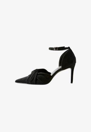 Fekete velúr magassarkú cipő hegyes orral, elülső csomó részletgel és bokapánttal. Karcsú stiletto sarokkal és letisztult dizájnnal rendelkezik.