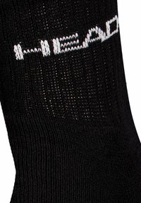 Black sock made of knit material featuring a ribbed texture. The brand name "HEAD" is prominently displayed in white woven lettering.