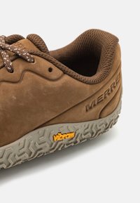 Brown leather sneaker with textured surface, round toe, matching laces, and a gray Vibram sole featuring a raised tread pattern and logo.