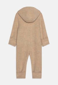 Beige fleece heldragt med hætte, lange ærmer og manchetter ved anklerne. Blød tekstur, minimalistisk design, fremtrædende syninger langs sømmene.
