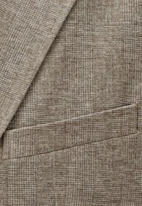 Tessuto marrone con motivo a trama, dall'aspetto tessuto e strutturato. Presenta una tasca nell'angolo in basso a destra, che valorizza il design definito.