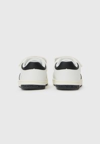 Une paire de baskets Calvin Klein blanches et noires vues de l'arrière sur un fond blanc.