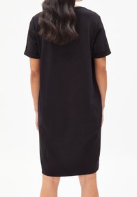 Czarna sukienka do kolan z krótkimi rękawami, charakteryzująca się luźnym krojem i miękką fakturą, wyrazistym dekoltem oraz podwiniętymi mankietami.