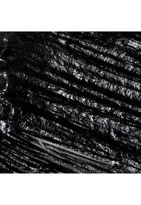 Surface brillante, noire et texturée avec des crêtes et des rainures irrégulières formant un motif brillant et irrégulier en vue rapprochée.