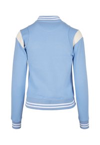 Šviesiai mėlynas džemperis su dryžuotu baltu ir mėlynu apykakle bei rankogaliais. Turi kontrastingus baltus pečių akcentus ir prigludusią formą.